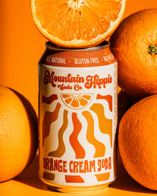Mountain Hippie Soda Co. Orange Cream Soda surrounded by oranges